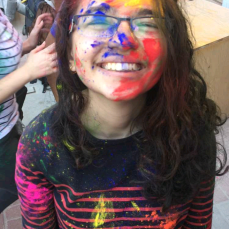 Young girl poses after an Indian Holi festival completely covered in colorful paint splatters