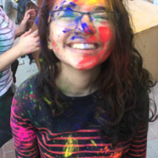 Young girl poses after an Indian Holi festival completely covered in colorful paint splatters