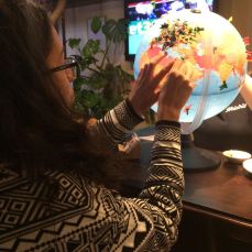 Young girl placing a pin point on her country of origins, Egypt, on a globe in a restaurant in Riga, Lativa.